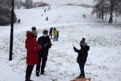 policjantka przekazuje dziecku i jego opiekunce zasady bezpieczeństwa na zaśnieżonym pagórku w parku