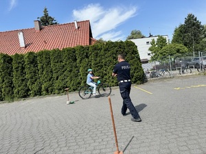 uczennica pokonuje tor przeszkód podczas egzaminu na kartę rowerową obok stoi policjant