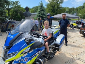 dziecko siedzi na policyjnym motocyklu, za nim stoją policjanci
