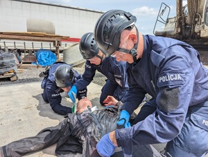 trzech policjantów opatrujący poszkodowanego