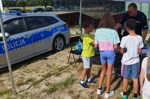 technik kryminalistyki pokazuje dzieciom jak zbiera ślady na miejscu przestępstwa