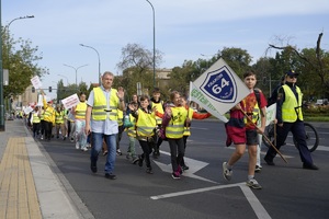 dzieci uczestniczące w przemarszu wraz z opiekunem w kamizelkach odblaskowych maszerują przez ulice Krakowa