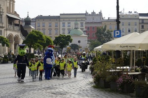 maskotki policji i straży miejskiej prowadzące dzieci w odblaskach przez krakowski rynek