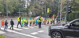 Przemarsz dzieci przez przejście dla pieszych, na pierwszym planie policjant kierujący ruchem 2