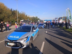 2 dwa radiowozy oraz policjanci w miejscu startu uczestników biegu