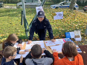 dzieci w towarzystwie policjantki wykonują rysunki