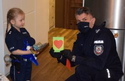 Komendant Miejski Policji w Krakowie wręcza dziewczynce kartkę okolicznościową z sercem