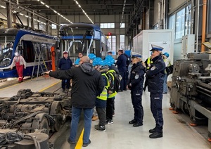 policjanci wraz z uczniami podczas zwiedzania zajezdni tramwajowej