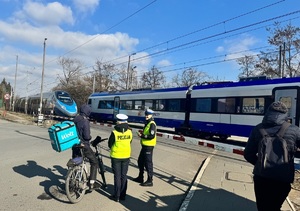 policjantki rozmawiające z rowerzysta przy przejeździe kolejowym podczas przejazdu pociągu