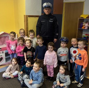 policjant wraz z grupą przedszkolaków uczestniczacych w zajęciach edukacyjnych