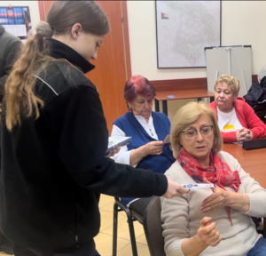 uczniowie klasy mundurowej wręczają seniorom ulotki informacyjne