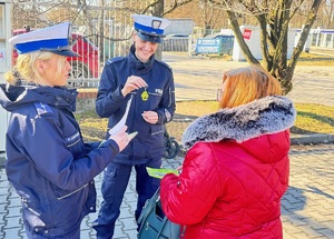 policjanci wręczają kobiecie element odblaskowy