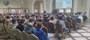 uczniowie słuchają prowadzonej przez policjanta prelekcji