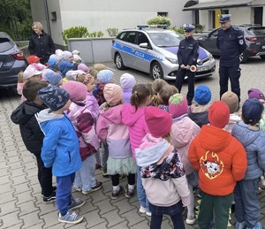 przedszkolaki i policjanci przed budynkiem przedszkola w tle radiowóz