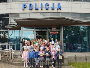 wspólne zdjęcie dzieci z policjantem przed budynkiem komisariatu