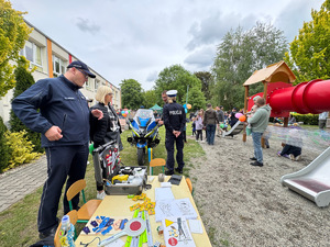policjant i kobieta przy policyjnym stoisku profilaktycznym w tle policjantka ruchu drogowego uczestnicy pikniku