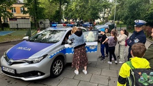 dzieci w towarzystwie policjantów oglądają wnętrze radiowozu
