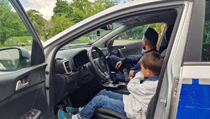 dziecko siedzi za kierownicą radiowozu obok siedzi policjant