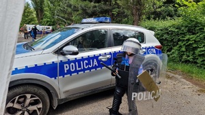 przy radiowozie dziecko w elementach umundurowania policjanta zabezpieczającego imprezy masowe