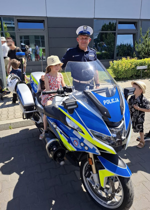 Na terenie MPK dziewczynka w towarzystwie policjanta ruchu drogowego sziedzi na policyjnym motocyklu