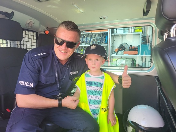 w radiowozie policjant i dziecko w policyjnej kamizelce odblaskowej