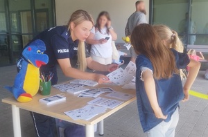 dziewczynki otrzymują od policjantki karty z rebusami i zagadkami