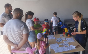 policjantka rozdaje dzieciom i ich opiekunom materiały edukacyjne
