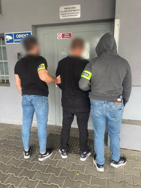 dwóch nieumundurowanych policjantów prowadzi zatrzymanego do policyjnego aresztu