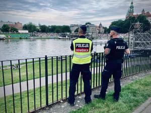 dwóch umundurowanych policjantów obserwuje widzów zgromadzonych na brzegu Wisły