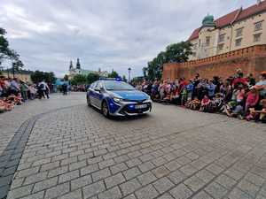 oznakowany radiowóz stojący na ulicy w rejonie Wawelu. Wokół widać zgromadzone osoby