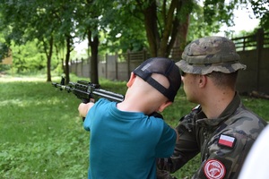 chłopiec w towarzystwie żołnierza ogląda karabin