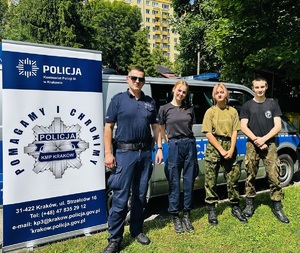umundurowany policjant w towarzystwie uczniów klasy mundurowej jednej ze szkół