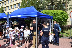 grupa dzieci oraz policjanci znajdujący się przy policyjnym stanowisku profilaktycznym