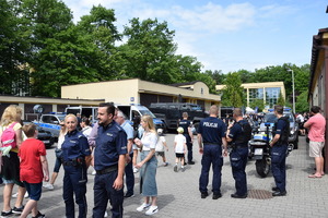 policjanci oraz przybyli goście idący między pojazdami policyjnymi
