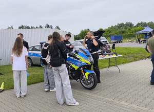 uczestnicy meetingu przy policyjnym motocyklu rozmawiają z policjantem drogówki