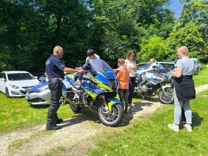 Policjant stojący przy motocyklu rozmawia z uczestnikami festynu