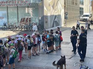dzieci stojące na placu przed dworcem głównym w towarzystwie policjantów