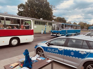 Policyjny radiowóz na tle dwoch autobusów