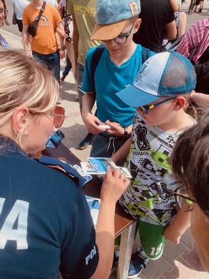 Polijantka podaje dzieciom ulotki