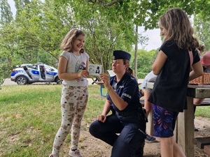 dziewczynka z odbitką swojej dłoni na karcie w towarzystwie policjantki
