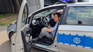 Młody turysta pozuje w radiowozie policyjnym