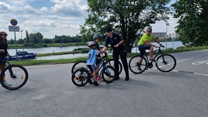 Policjantka wręcza naklejkę chłopcu na rowerze