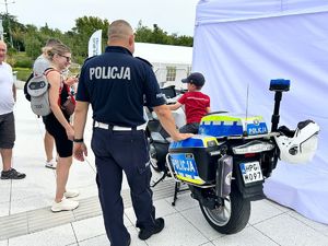 Policjant stoi obok chłopca na motocyklu
