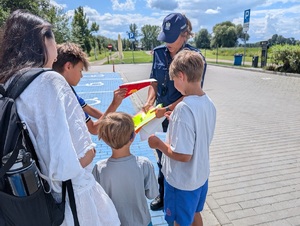 Policjantka rozdaje dzieciom ulotki