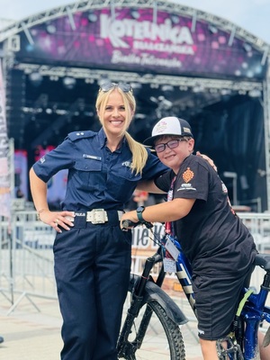 policjantka pozuje do zdjęcia z chłopcem, w tle scena