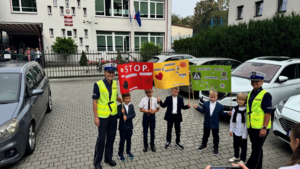 dzieci z transparentami i policjantki podczas akcji Bezpieczna droga do szkoły