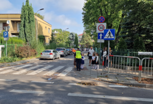 policjantka i dzieci z opiekunami przy przejściu dla pieszych