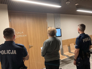kobieta i obok niej dwóch policjantów przed salą rozpraw