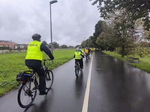 Policjant na rowerze zamyka przejazd kolumny