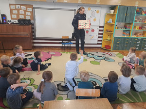 umundurowana policjantka prezentująca dzieciom tablicę z numerami alarmowymi